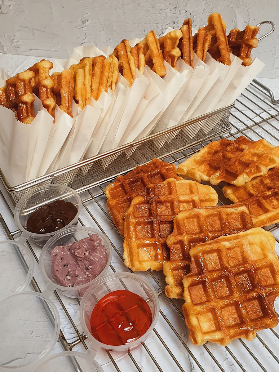 Crispy croffles and waffles cooling on a rack with dipping sauces