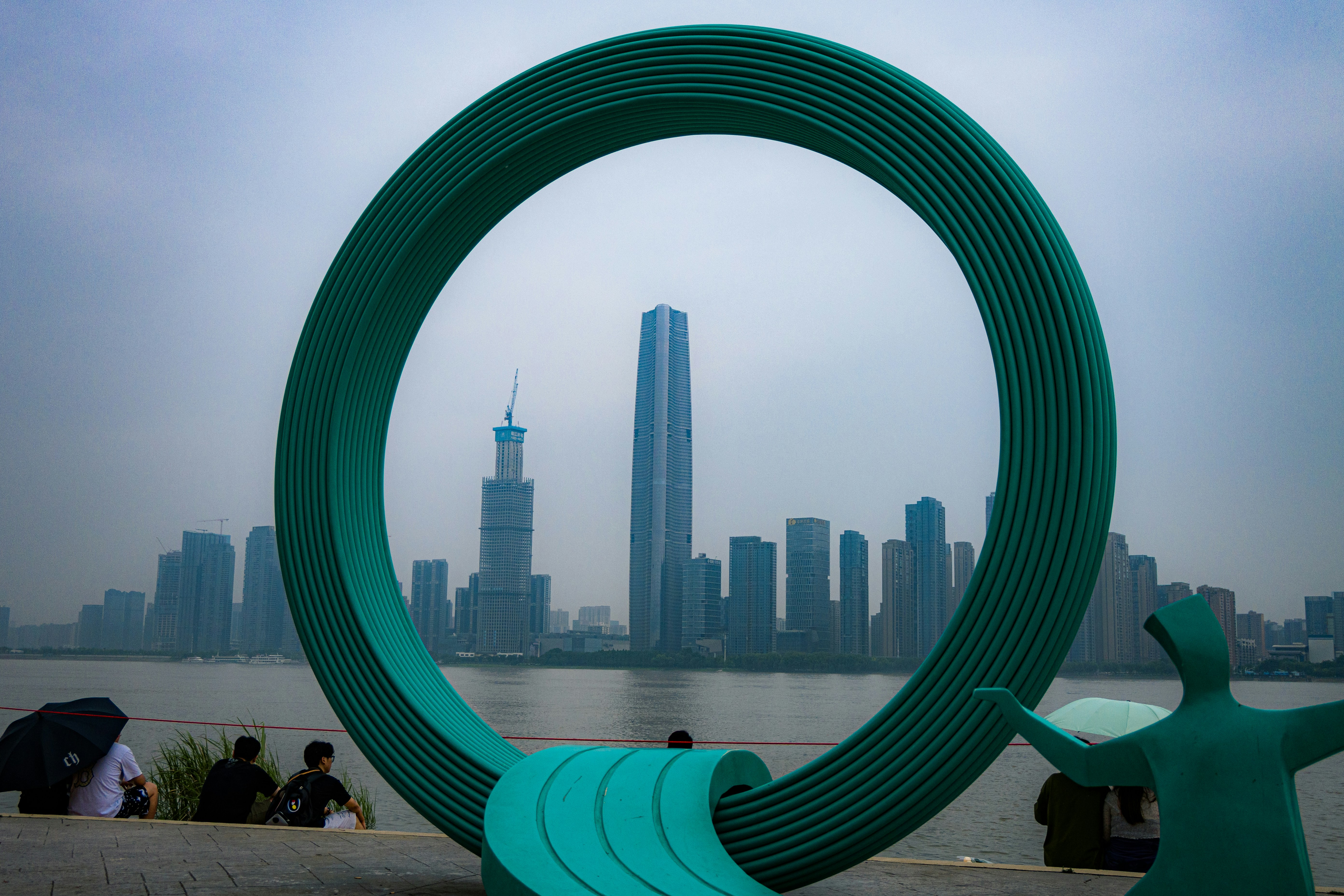 A green sculpture with a city in the background