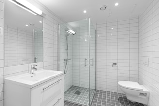 A white bathroom with a walk in shower next to a toilet