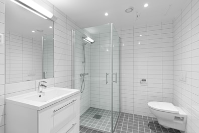 A white bathroom with a walk in shower next to a toilet