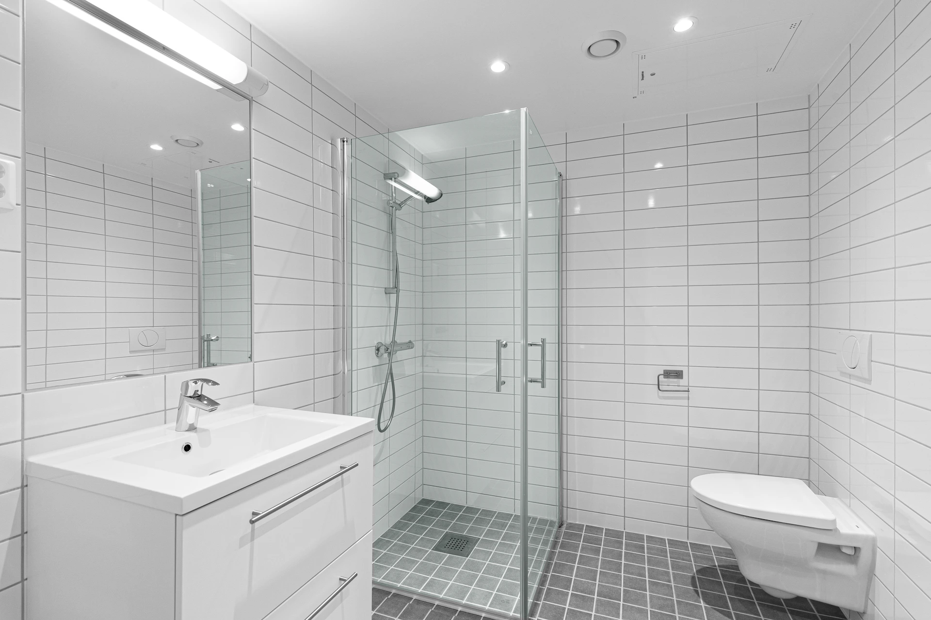 A white bathroom with a walk in shower next to a toilet