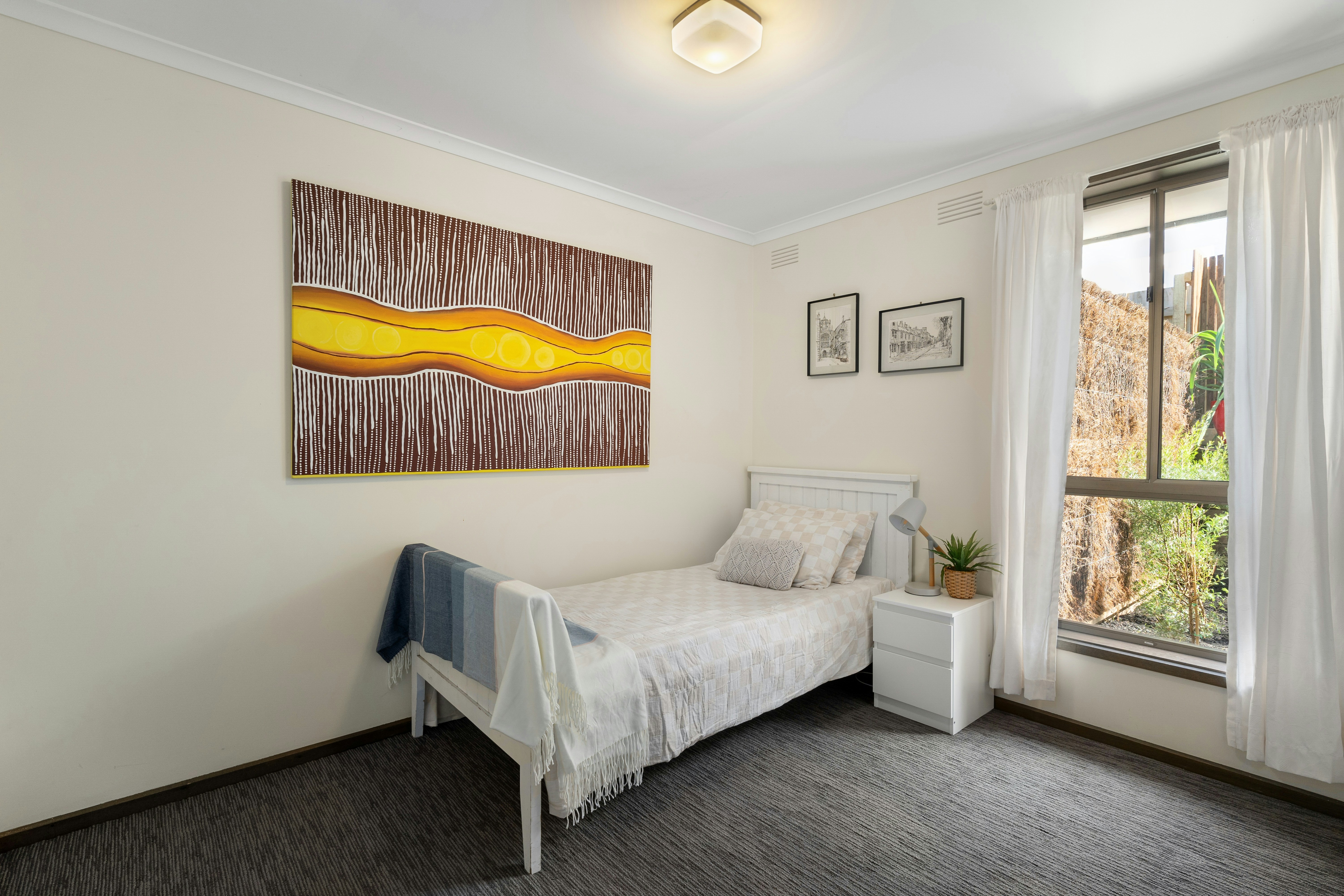 A bedroom with a bed and a painting on the wall