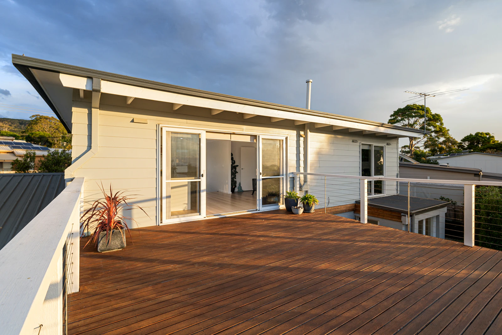A wooden deck attached to a house, overlooking a backyard
