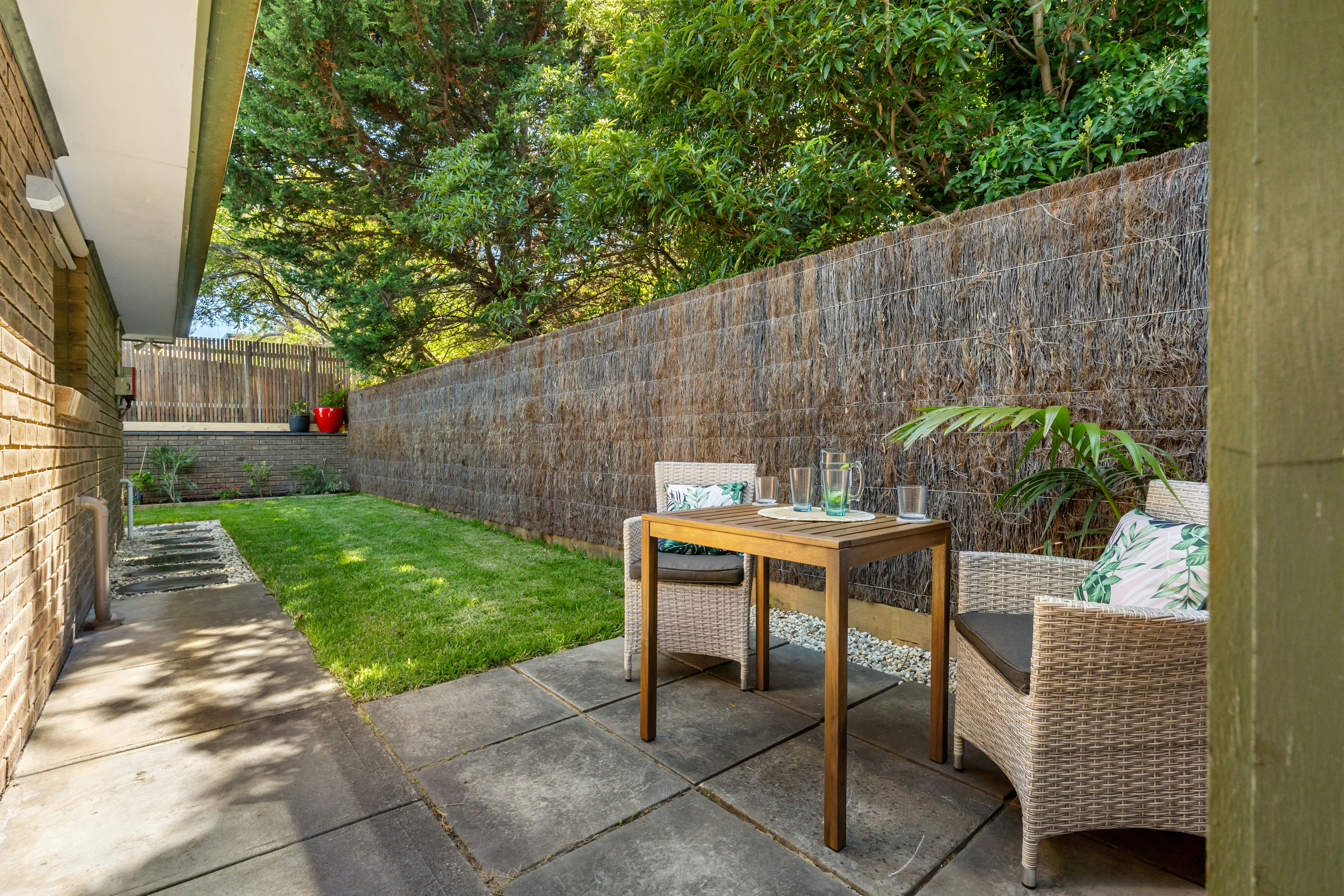 A patio with a table and chairs next to a brick wall