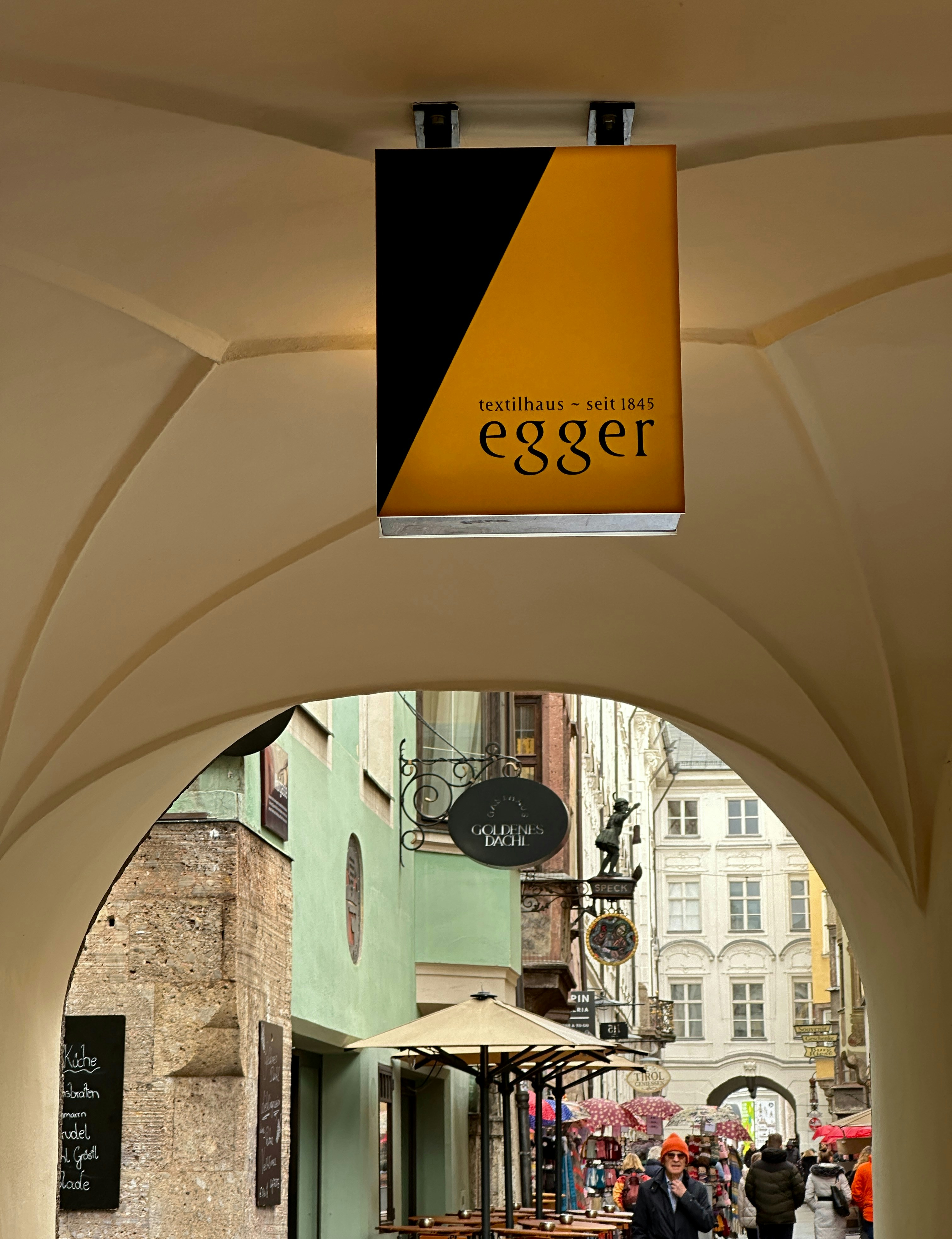 An archway with a sign hanging from it's side