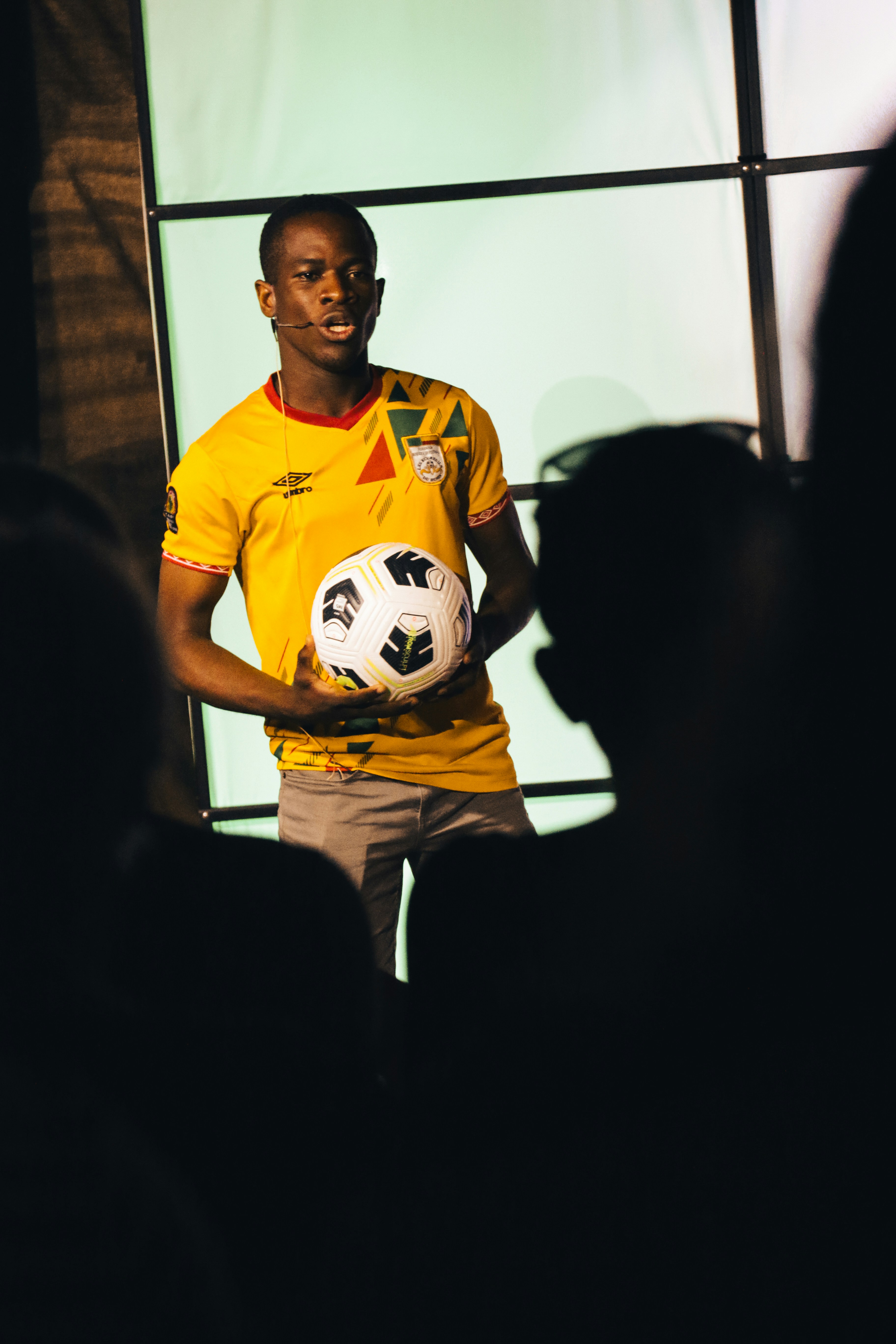 Soccer player in professional photoshoot holding ball, studio backdrop with dramatic sports photography lighting