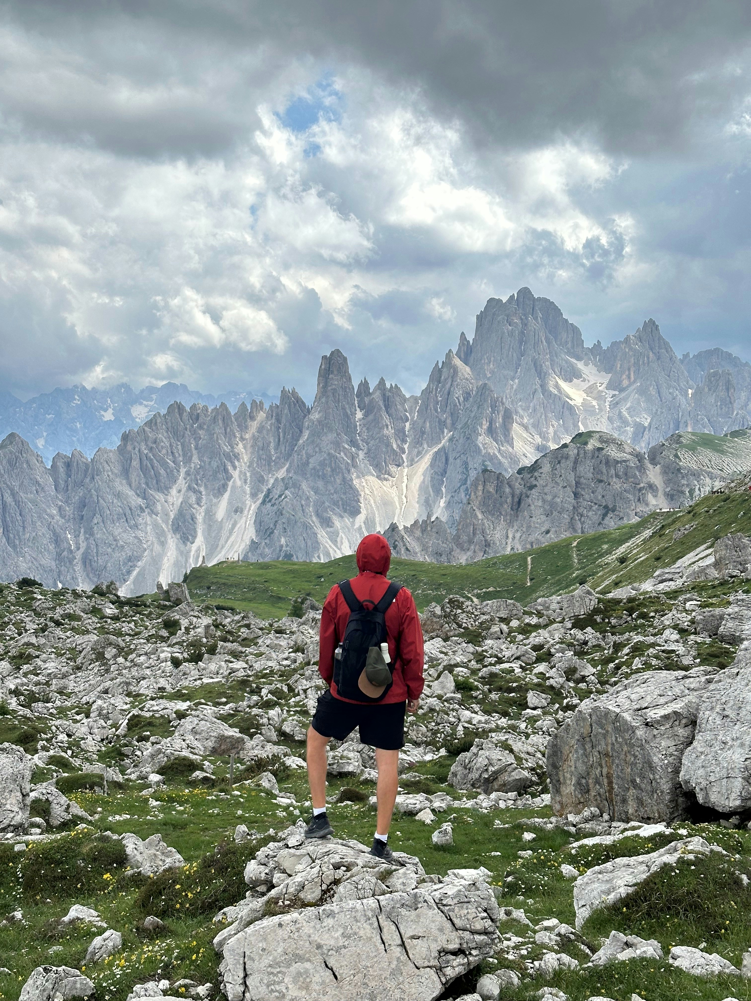 Un hombre con una chaqueta roja y pantalones cortos negros subiendo una montaña