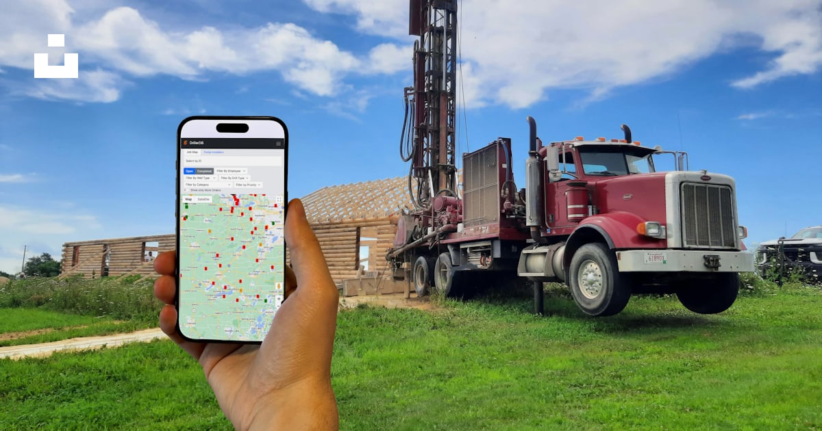 A person holding a cell phone in front of a drilling rig photo – Free ...