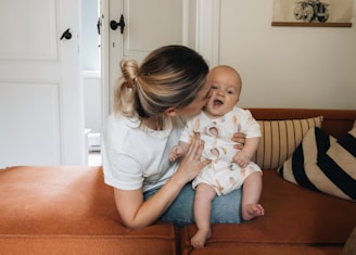 A woman sitting on a couch holding a baby