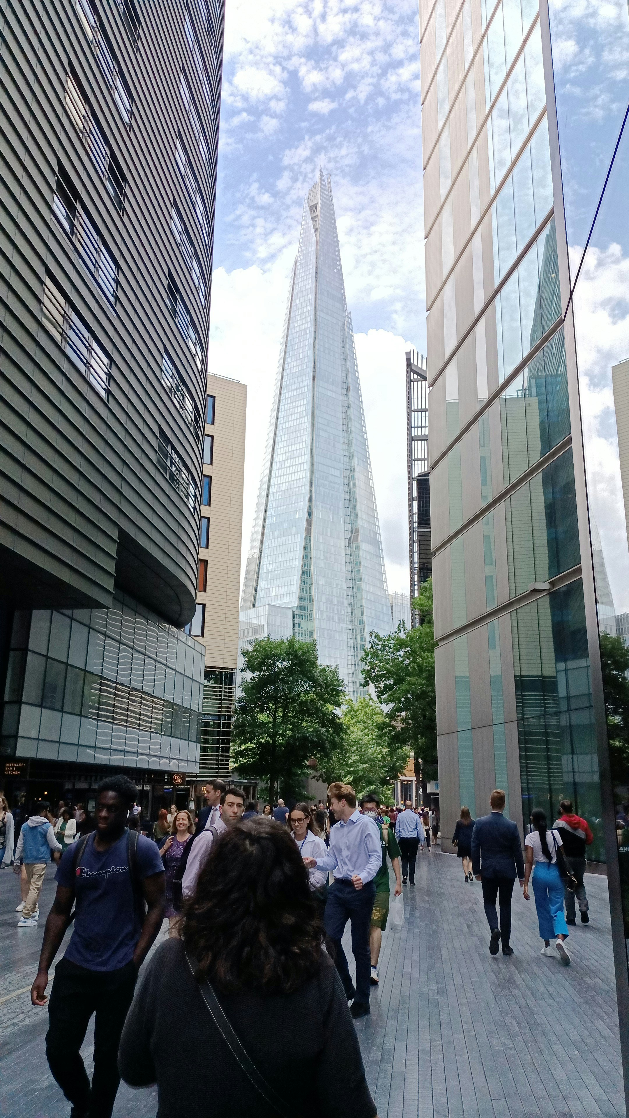 Un groupe de personnes marchant sur un trottoir à côté de grands immeubles