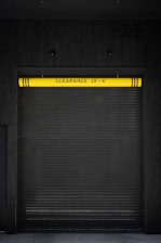 A closed garage door with a yellow sign on it