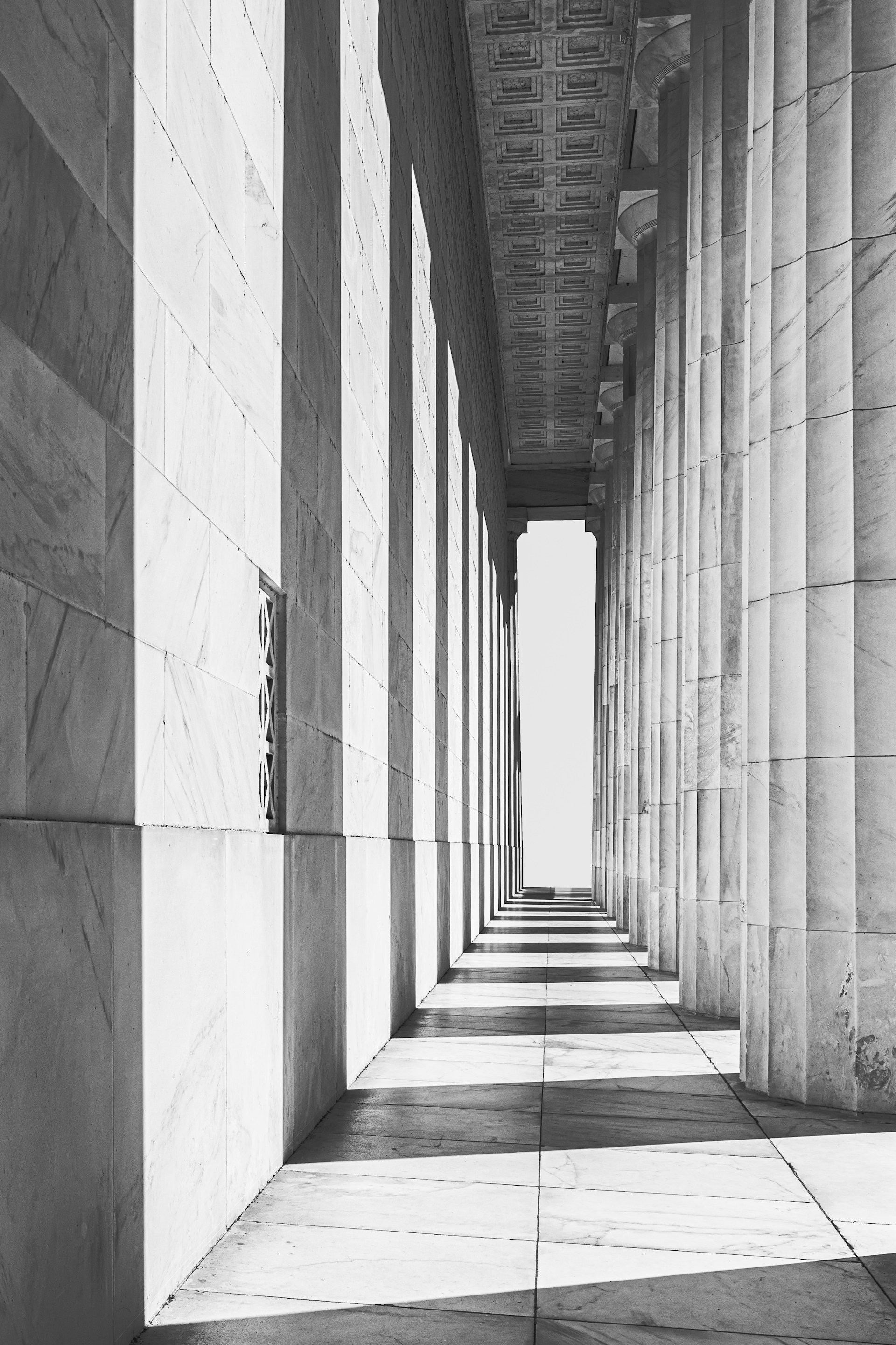 Black and white photograph of a long hallway lined with columns