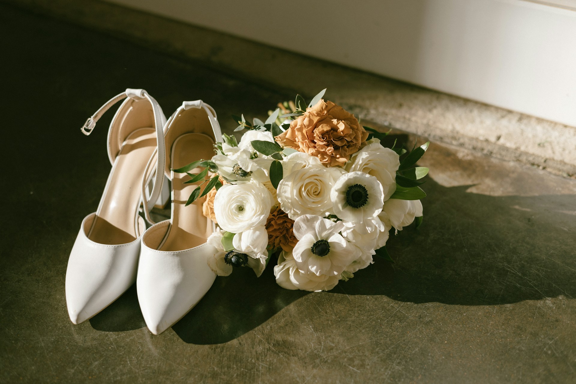 A bouquet of flowers sitting next to a pair of white shoes