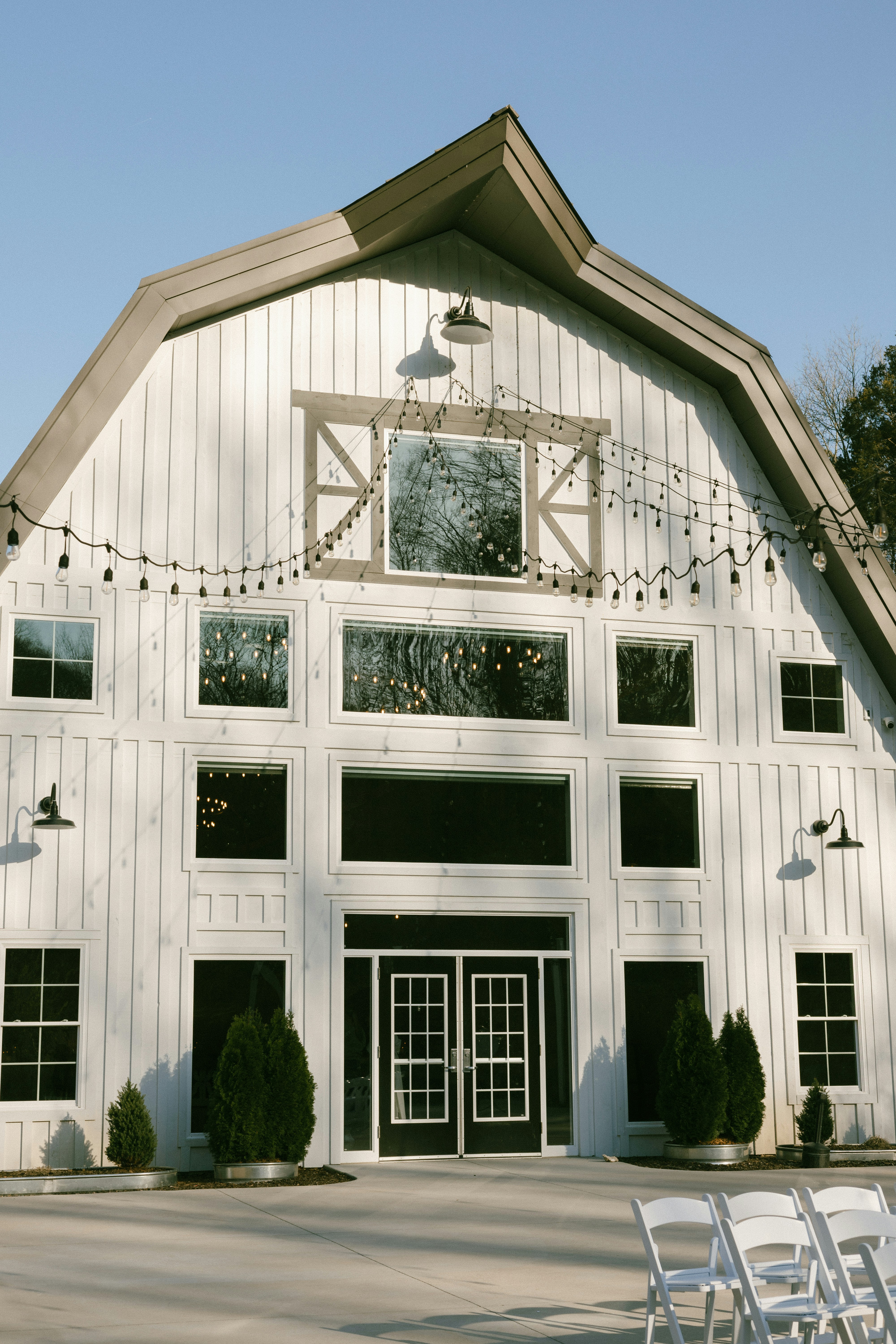 A large white barn with chairs in front of it