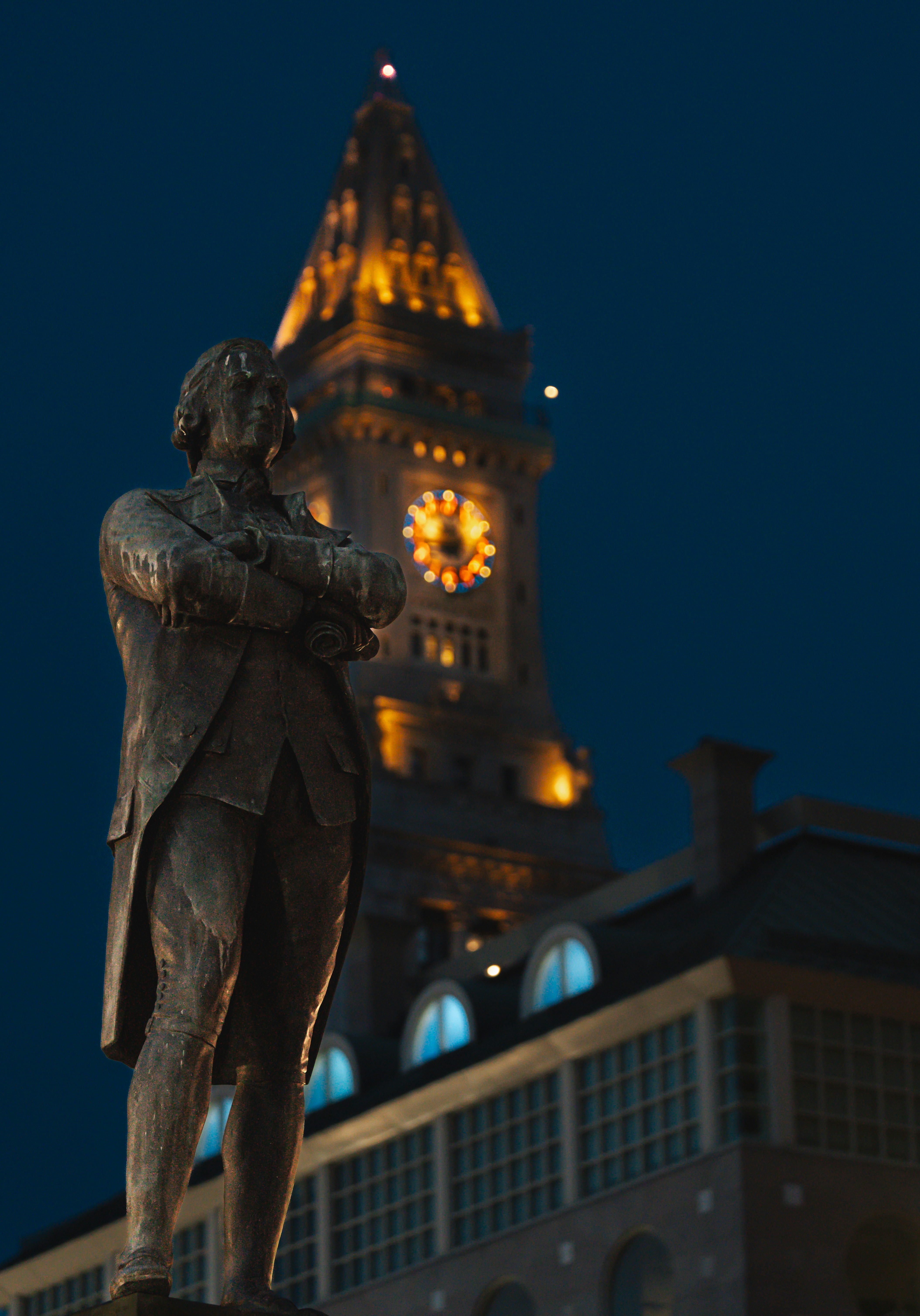 A statue of a man standing in front of a clock tower