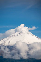 A very tall mountain with a cloud in the sky