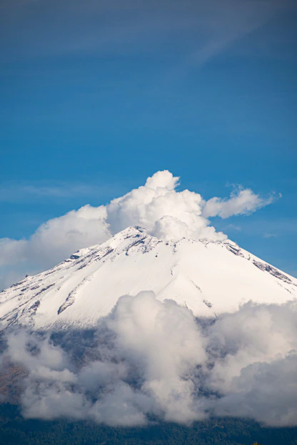 A very tall mountain with a cloud in the sky