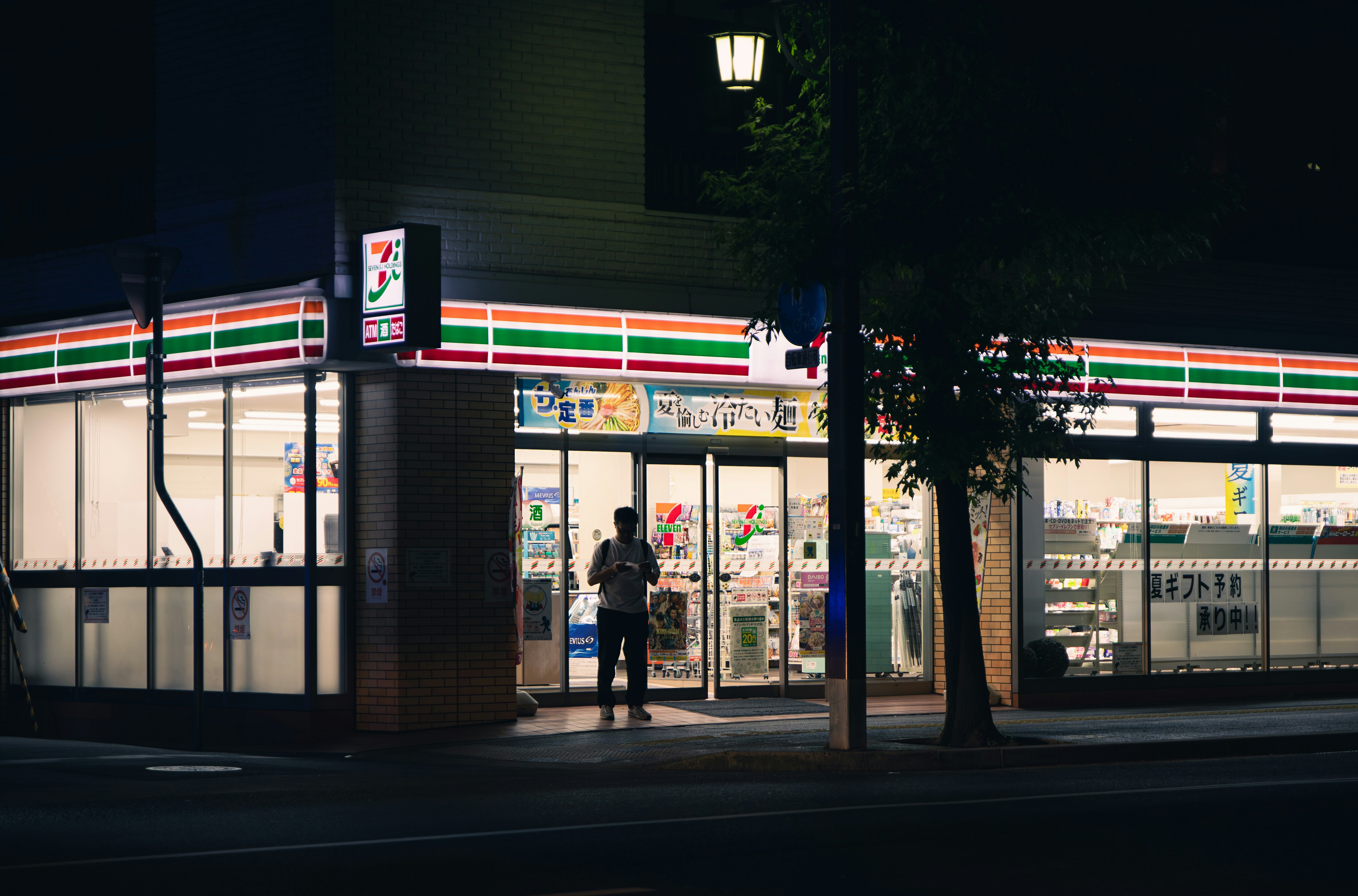 A person standing outside of a store at night