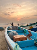 A blue boat sitting on top of a sandy beach
