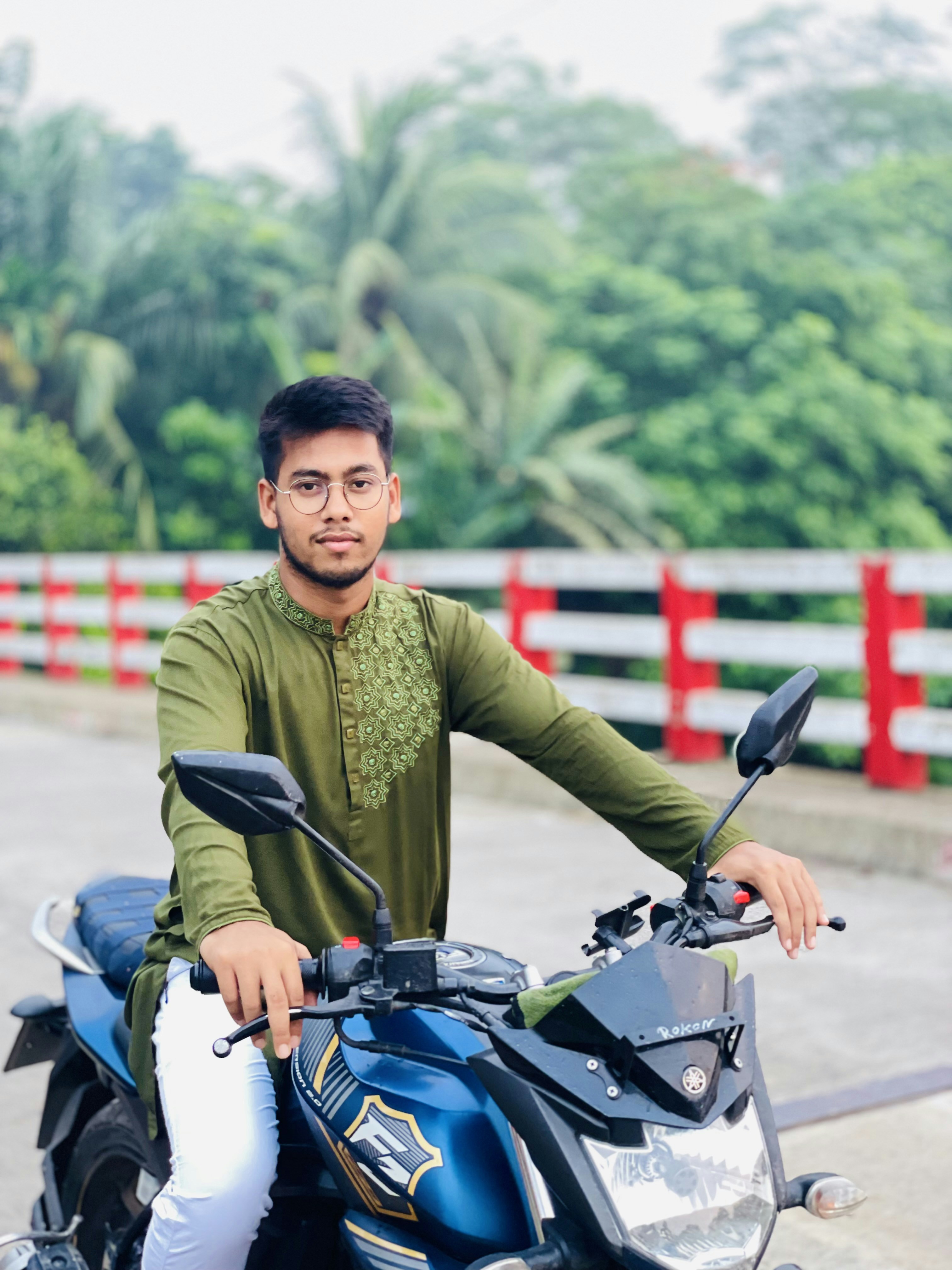 Seorang pria duduk di atas sepeda motor biru