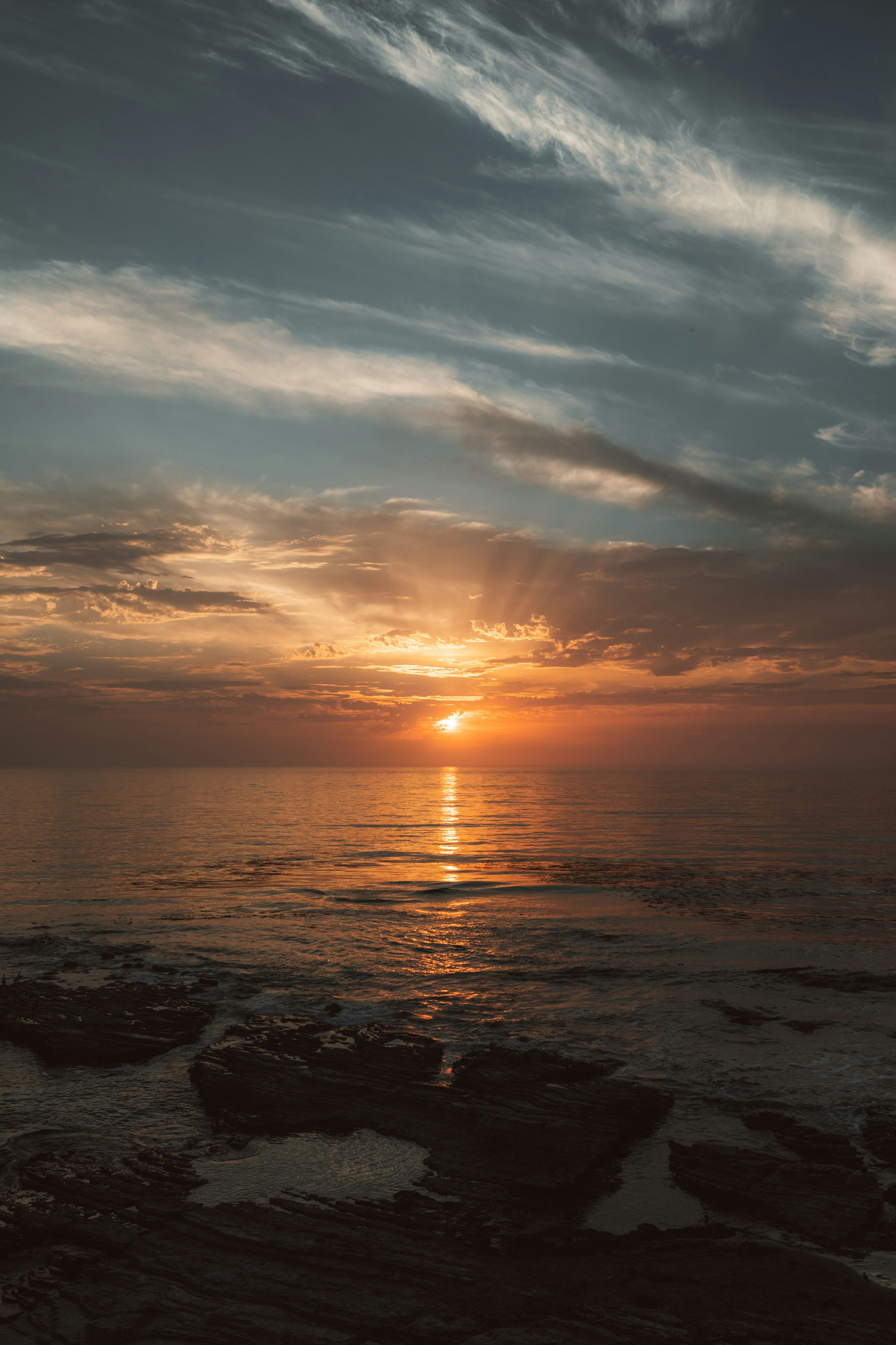 Die Sonne geht an einem bewölkten Tag über dem Meer unter