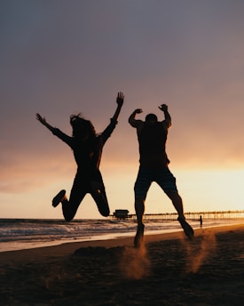 Two people jumping in the air on a beach