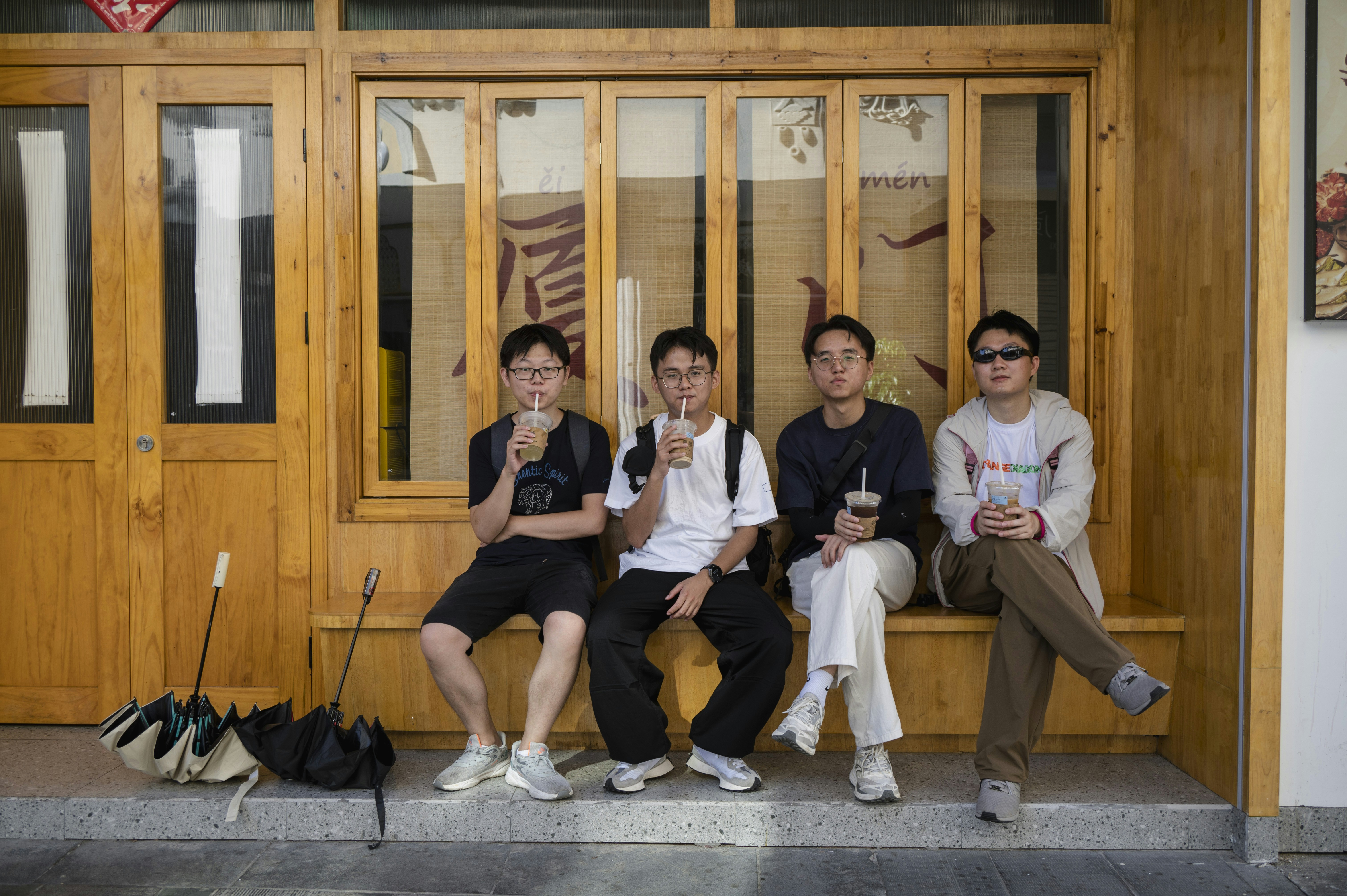 A group of people sitting on a bench in front of a building