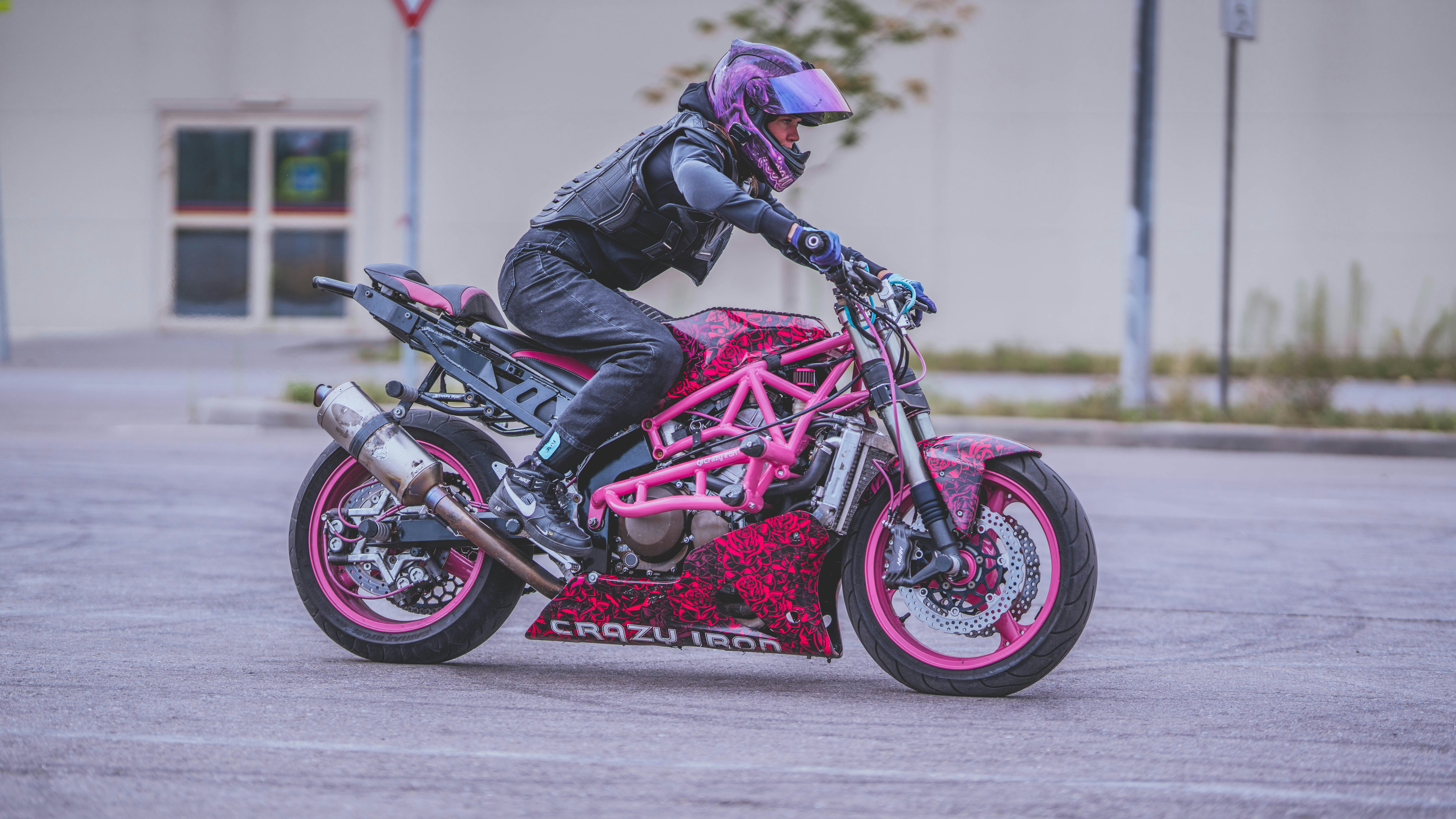 A man riding a pink motorcycle down a street