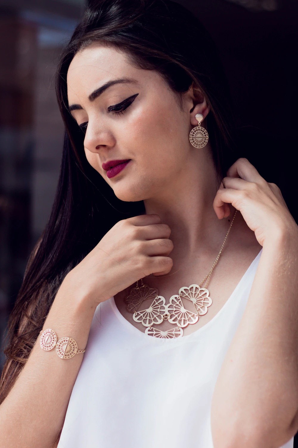 A person wearing a minimal necklace and earrings