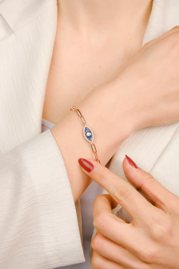 A woman wearing a bracelet with a evil eye on it