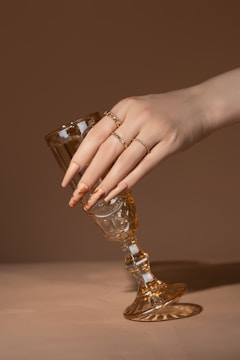 A woman's hand holding a wine glass on a table