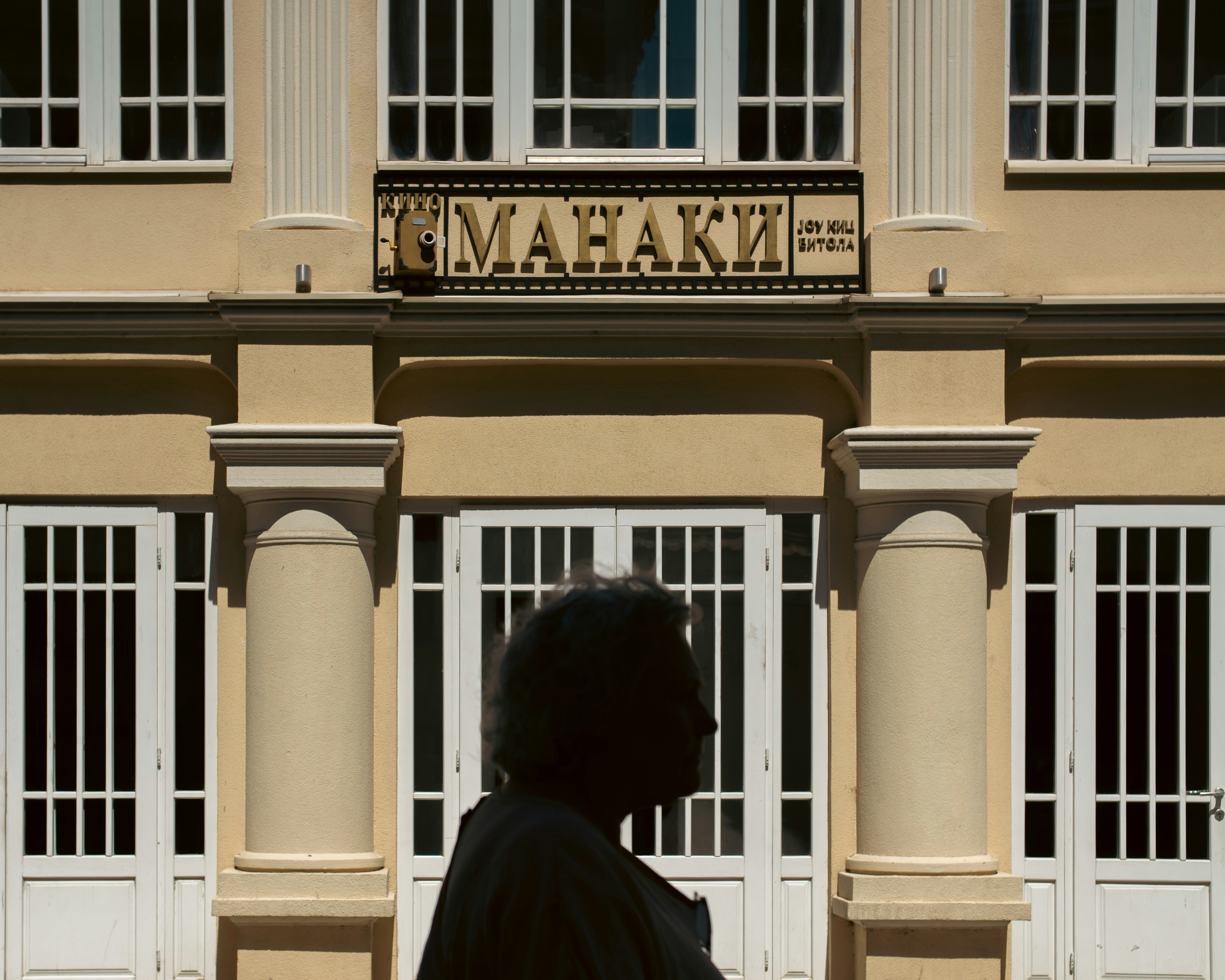 A man walking past a tall building with white windows