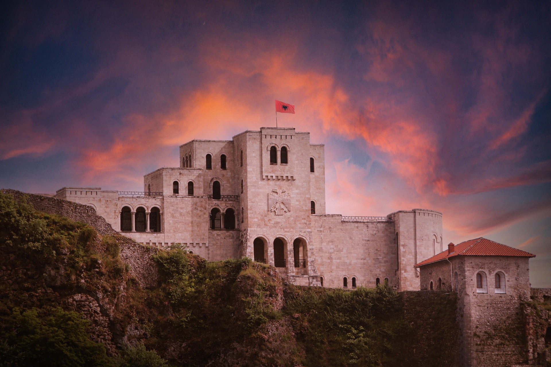 A castle on a hill with a sunset in the background