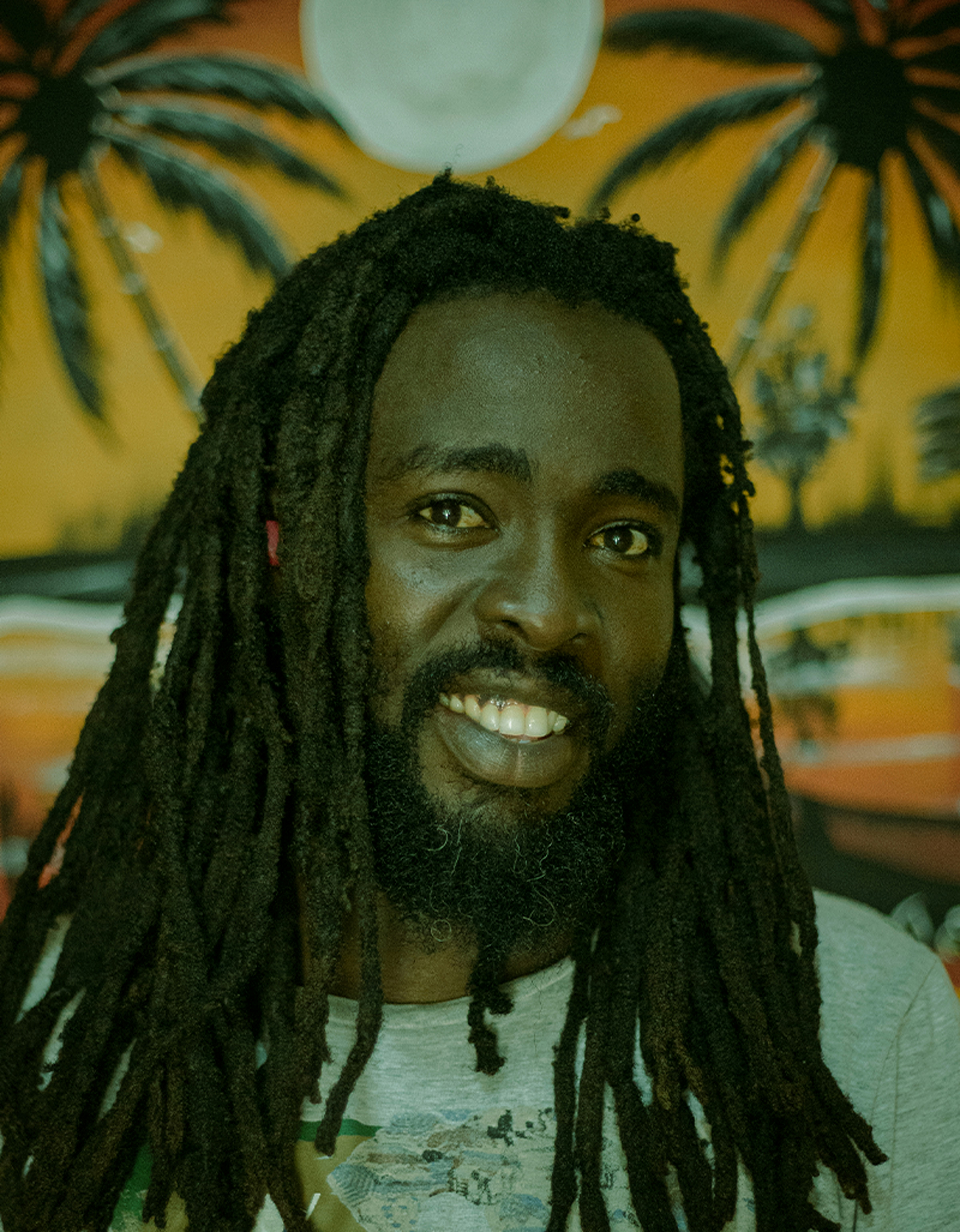 Portrait of Caribbean man with natural dreadlocks smiling confidently in outdoor setting