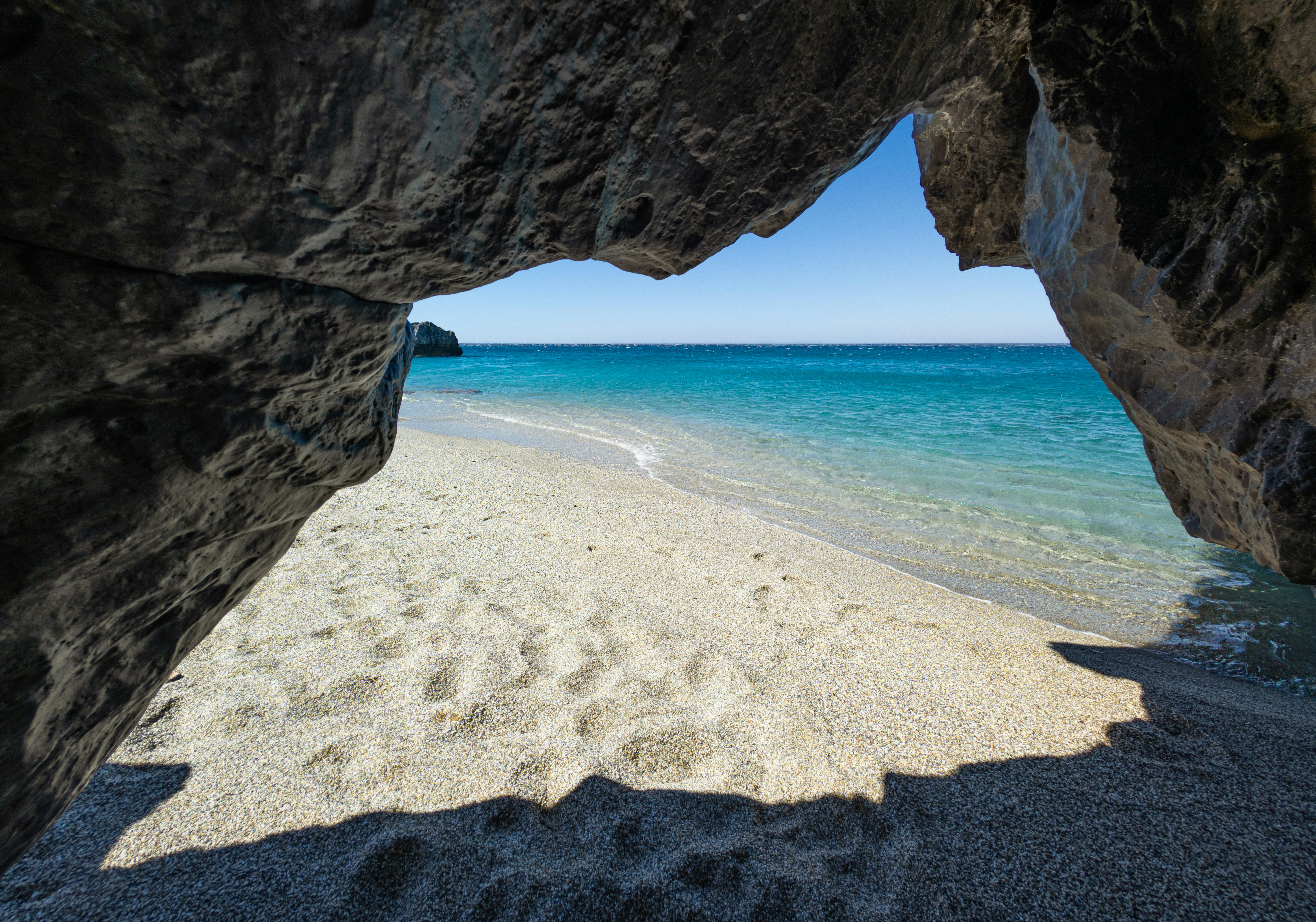 A view of a beach through an opening in a rock photo – Free Beach Image ...