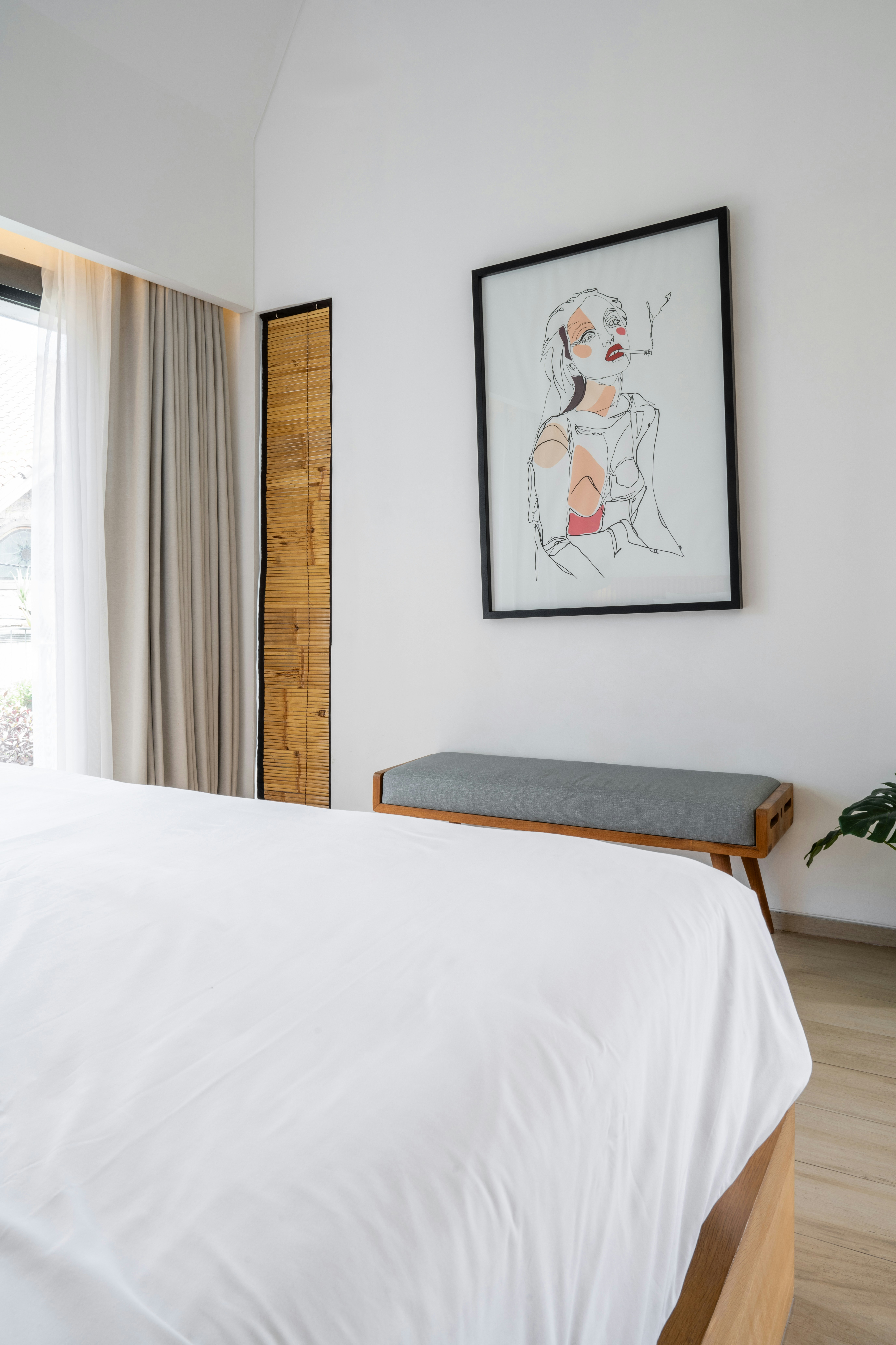 A bedroom with a white bed and a painting on the wall