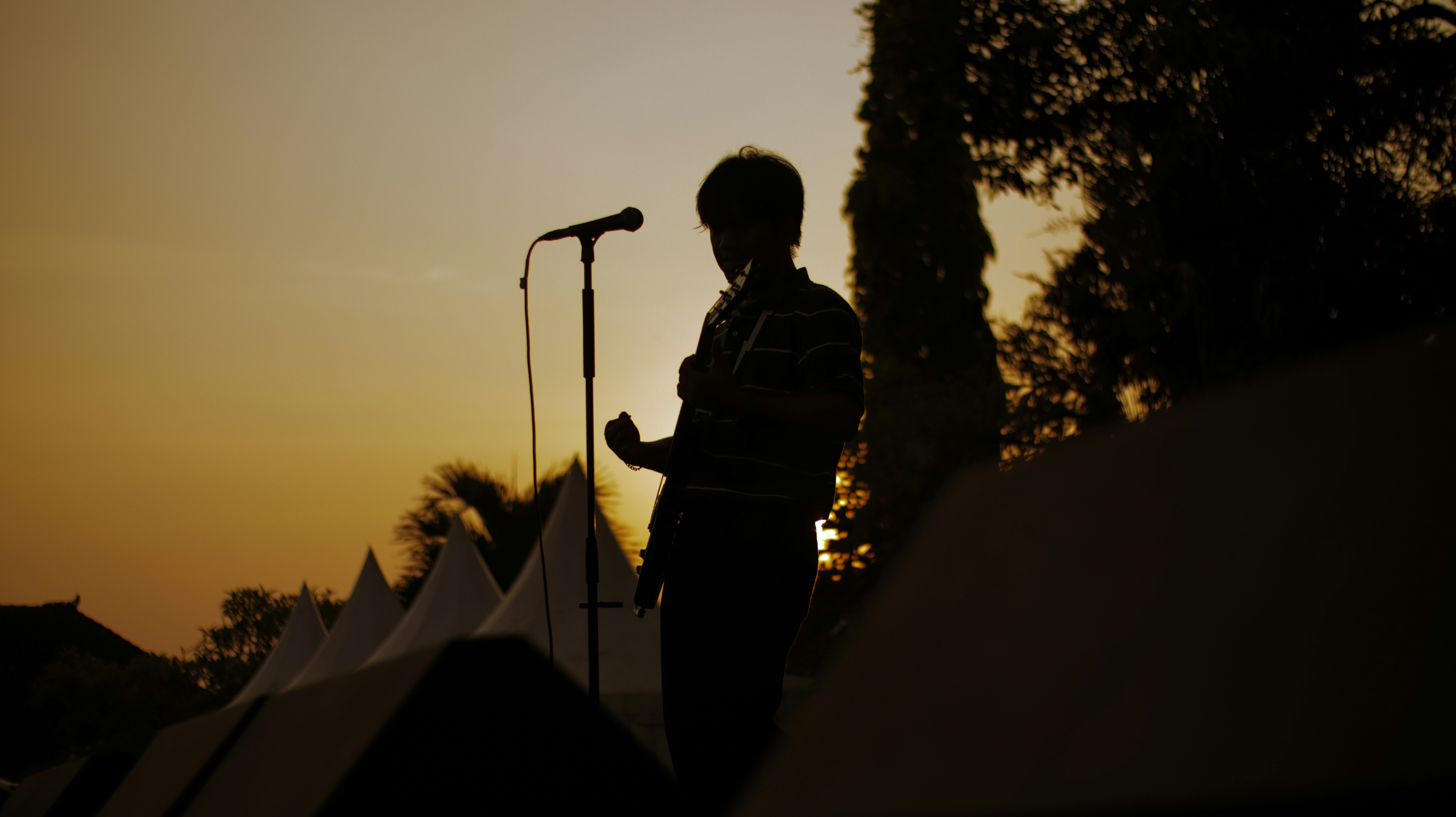 A passionate guitarist captivates the audience with his soulful performance on stage, under the bright concert lights. His music fills the air, creating an unforgettable experience.