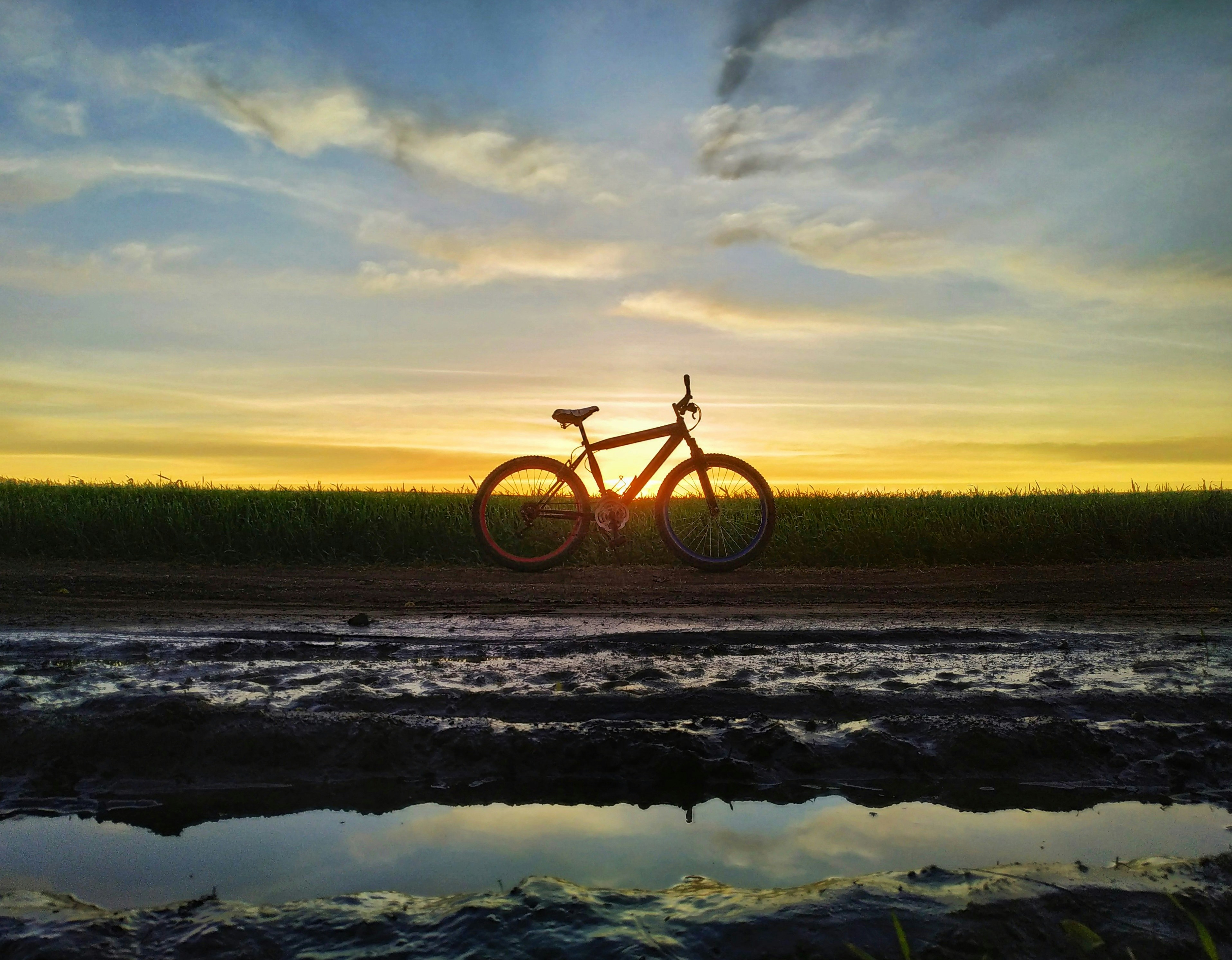 A bike is parked on the side of a muddy road