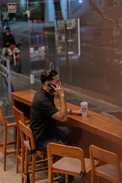 A man sitting at a table talking on a cell phone