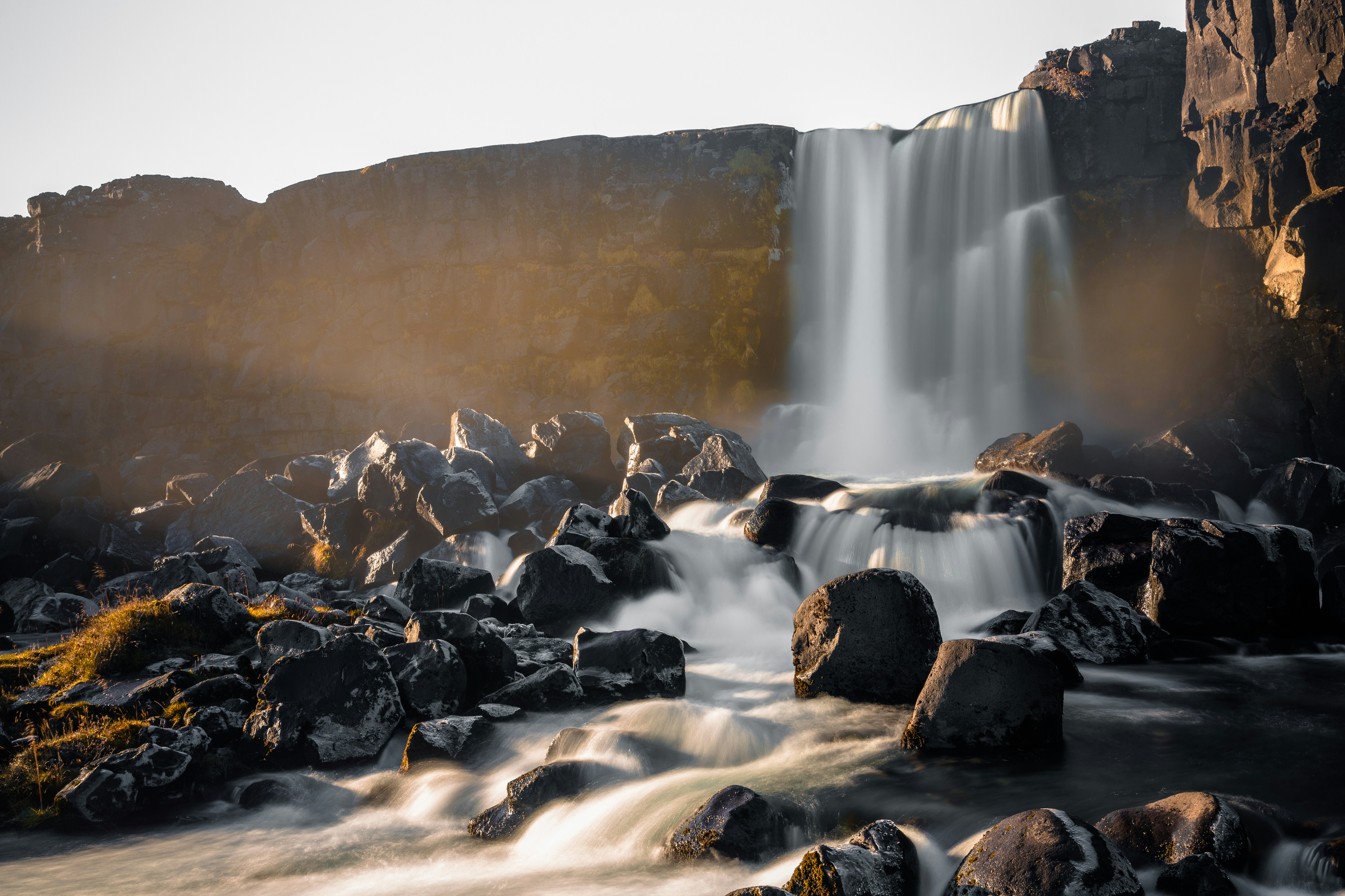 Una pequeña cascada está rodeada de rocas y hierba