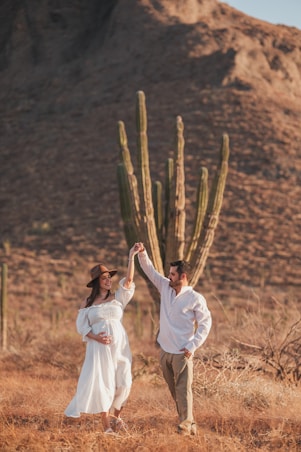 A man and woman holding hands in front of a cactus