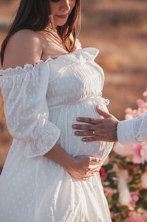 A pregnant woman in a white dress standing next to a man