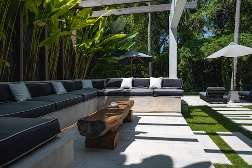 An outdoor living area with a couch, table and umbrellas