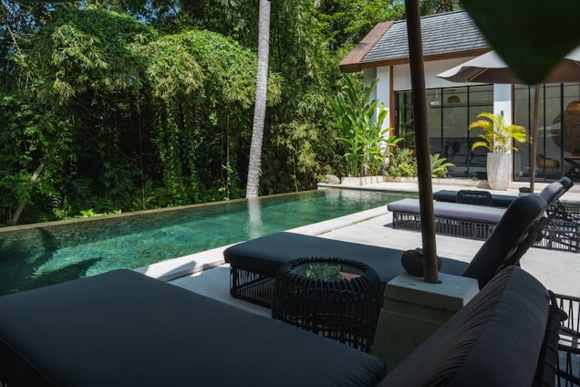 A pool with a lounge chair and umbrella next to it