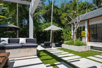 A patio with a couch, table and umbrellas