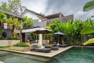 A pool with lounge chairs and umbrellas next to a house