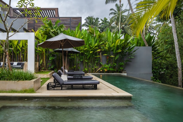 A pool with lounge chairs and umbrellas next to it