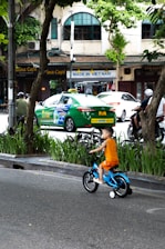 A young boy riding a blue bike down a street
