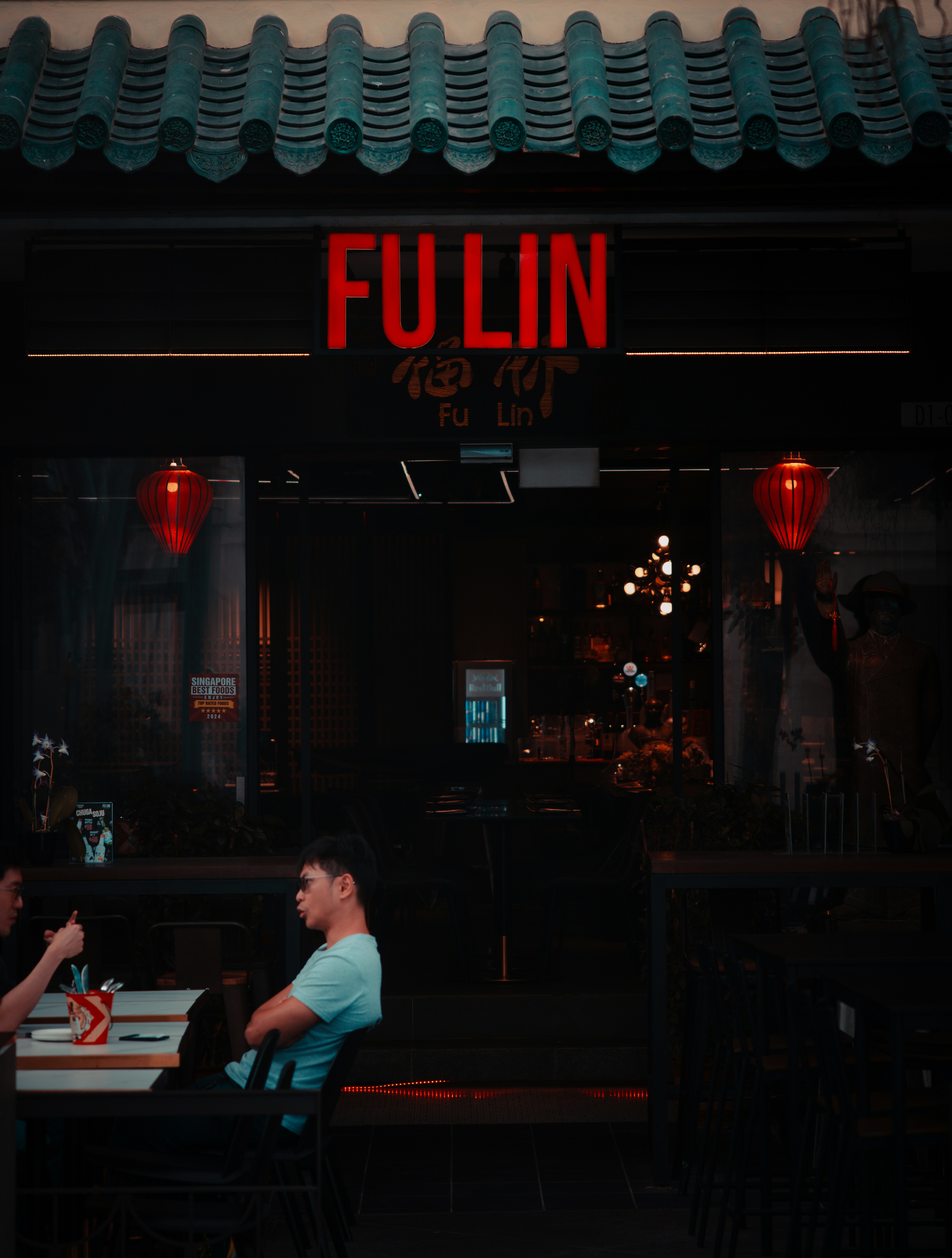 Two men sitting at a table in front of a restaurant