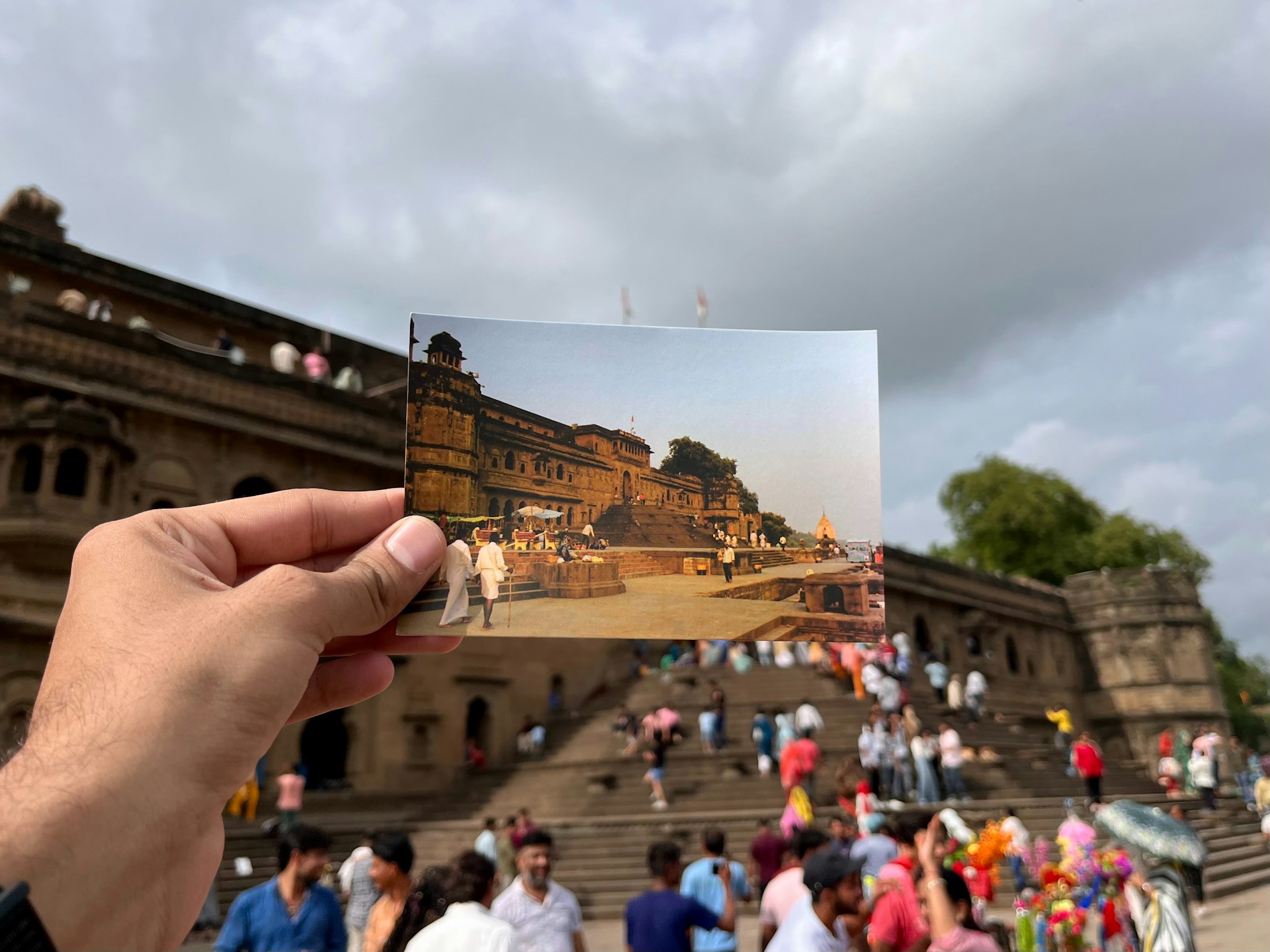 A person holding up a photo of a crowd of people